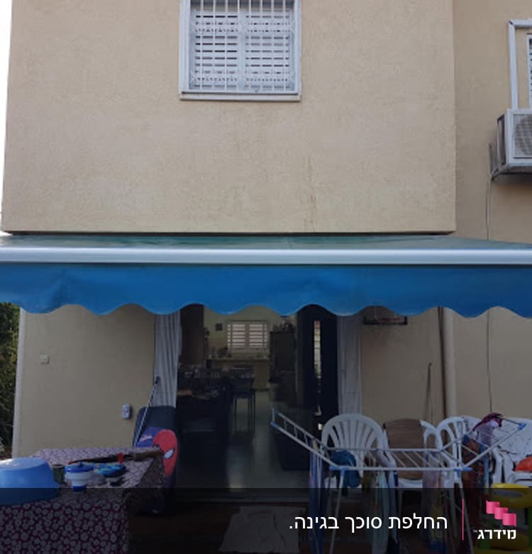 סוכך כחול מותקן מעל מרפסת עם רהיטים